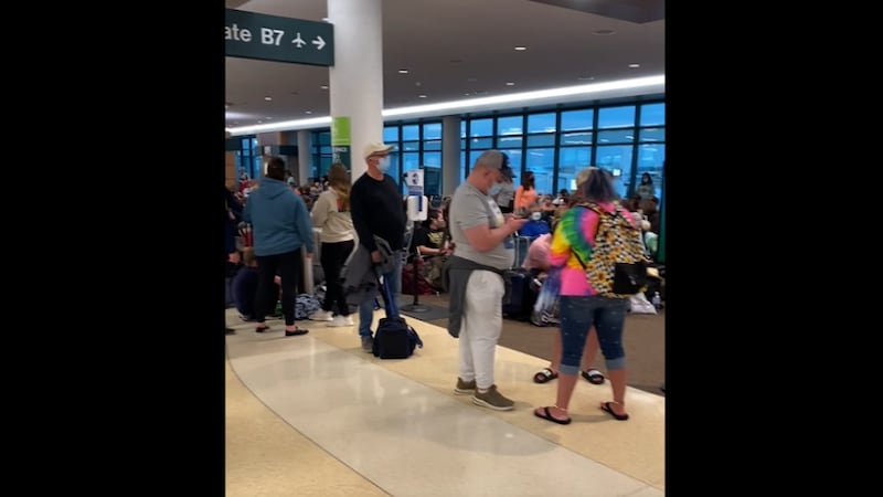 Masked passengers wait in line recently at Sarasota Bradenton International Airport. As of...